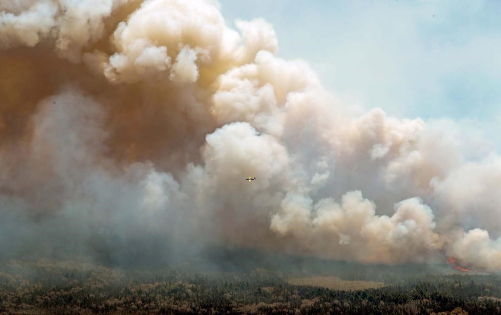 Nova Scotia's provincial firefighters are sending up helicopters this week to scan the Shelburne County wildfire to locate hot spots to put out. An aircraft (centre) disperses a mix of water and fire retardant over a fire near Barrington Lake, in Shelburne County, N.S., in a Wednesday, May 31, 2023, handout photo. THE CANADIAN PRESS/HO-Communications Nova Scotia **MANDATORY CREDIT**