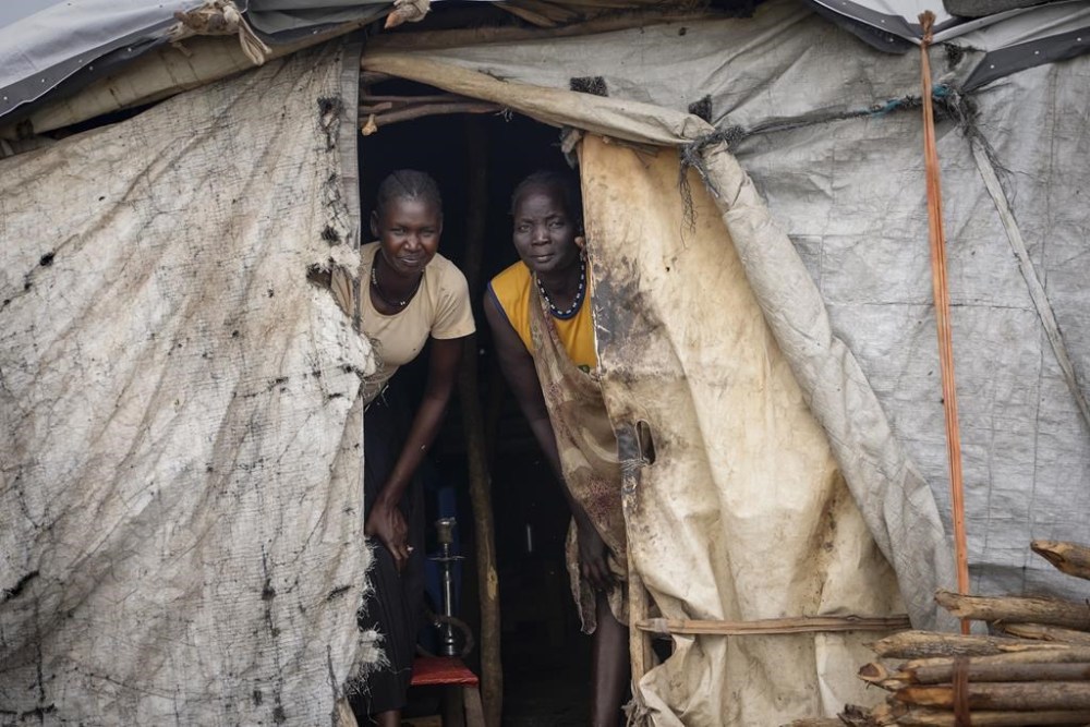 Two women peer out from their house in Kowach village in Canal Pigi county, Jonglei State, South Sudan Friday, May 5, 2023.  (AP Photo/Sam Mednick)