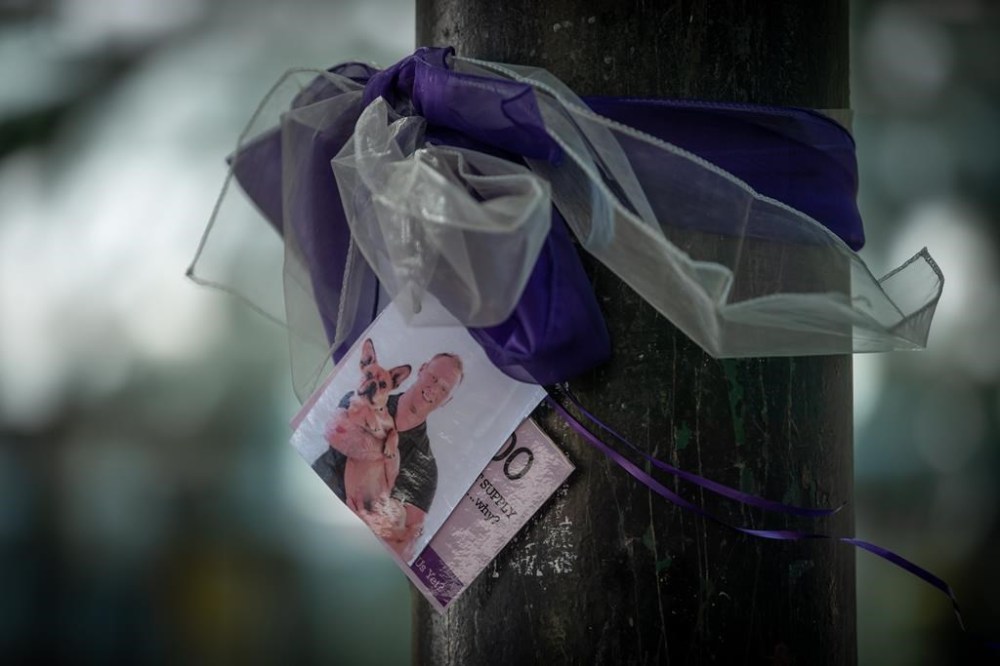 A photograph of a person who died due to an illicit drug overdose is tied to a tree with a purple ribbon by members of Moms Stop the Harm, in Vancouver, on Tuesday, August 16, 2022. THE CANADIAN PRESS/Darryl Dyck