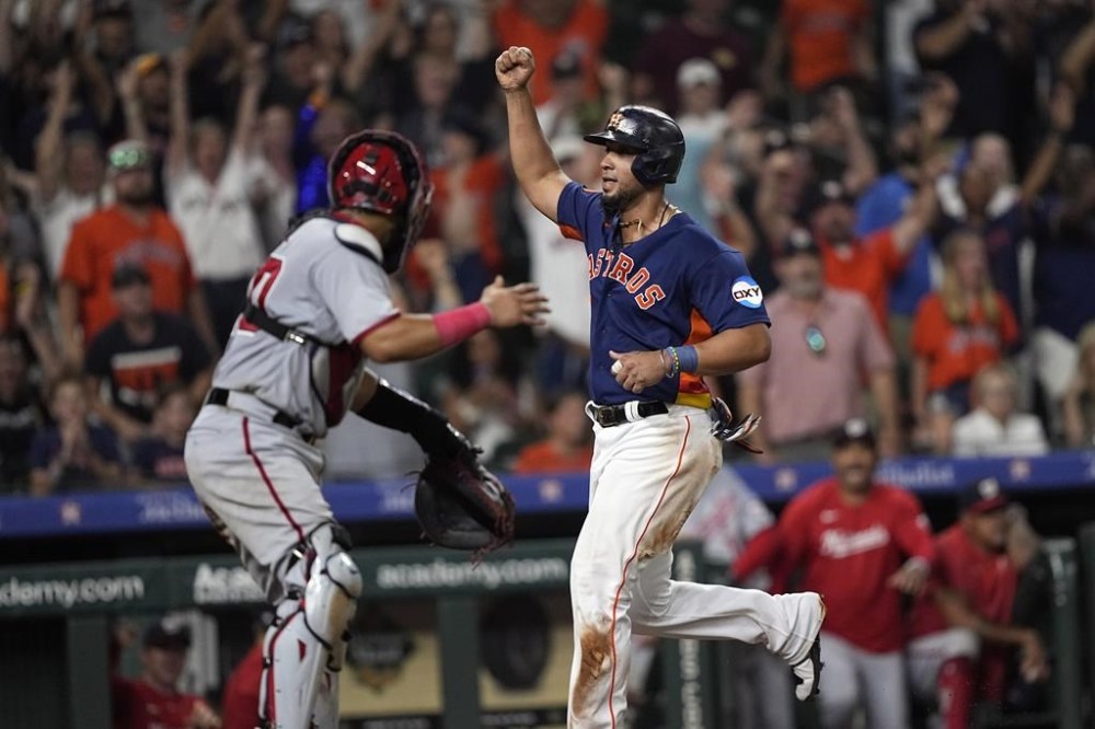 Houston Astros' Jose Abreu, right, celebrates as he scores the game-winning run as Washington Nationals catcher Keibert Ruiz looks back during the ninth inning of a baseball game Wednesday, June 14, 2023, in Houston. The Astros won 5-4. (AP Photo/David J. Phillip)
