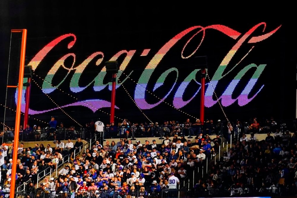 Fans sit in front of a rainbow-colored Coca-Cola sign during the seventh inning of a baseball game between the New York Mets and the New York Yankees on Wednesday, June 14, 2023, in New York. (AP Photo/Frank Franklin II)