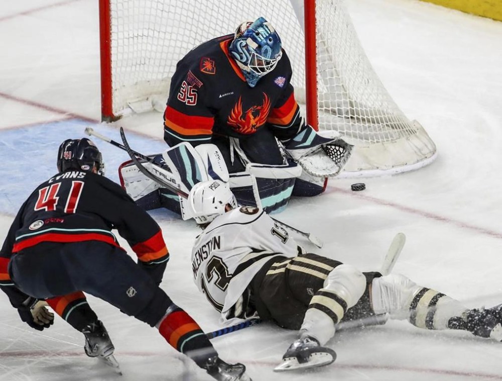 Coachella Valley Firebirds goaltender Joey Daccord (35) makes a stop as Hershey Bears forward Beck Malenstyn (13) slides down onto the ice during a Calder Cup Finals hockey game in Palm Desert, Calif., on June 10, 2023. Beset by pandemic revenue losses in a sport more driven by attendance than many others, the American Hockey League is back in a big way, setting revenue and playoff attendance records. The ongoing finals between Hershey and Coachella Valley is showing the potential of minor league hockey in North America. (Andy Abeyta/The Desert Sun via AP)