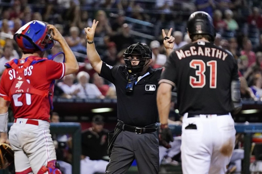 Umpire Nick Mahrley, center, calls a pitch clock violation against Philadelphia Phillies relief pitcher Craig Kimbrel (not shown) as Phillies catcher Garrett Stubbs, left, and Arizona Diamondbacks' Jake McCarthy (31) look on in the ninth inning of a baseball game Thursday, June 15, 2023, in Phoenix. (AP Photo/Ross D. Franklin)
