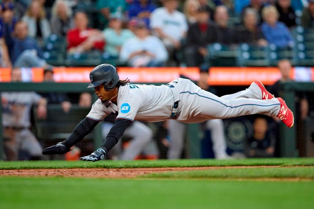 Miami Marlins' Jean Segura dives home to score on a sacrifice fly hit by Jonathan Davis against the Seattle Mariners during the eighth inning of a baseball game Wednesday, June 14, 2023, in Seattle. (AP Photo/John Froschauer)