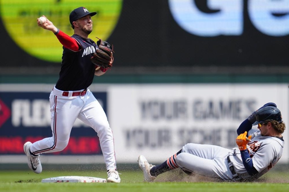 Minnesota Twins second baseman Kyle Farmer, left, throws to first base for a double play after getting out Detroit Tigers' Zach McKinstry, right, during the ninth inning of a baseball game Saturday, June 17, 2023, in Minneapolis. (AP Photo/Abbie Parr)
