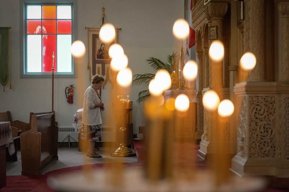 A woman pauses after lighting a candle before Sunday service at St. George's Ukrainian Orthodox Church, in Dauphin, Man., on Sunday, June 18, 2023. Residents of Dauphin sought solace at church services as they mourn 15 community members who died in a highway crash that also left 10 gravely injured. THE CANADIAN PRESS/Darryl Dyck