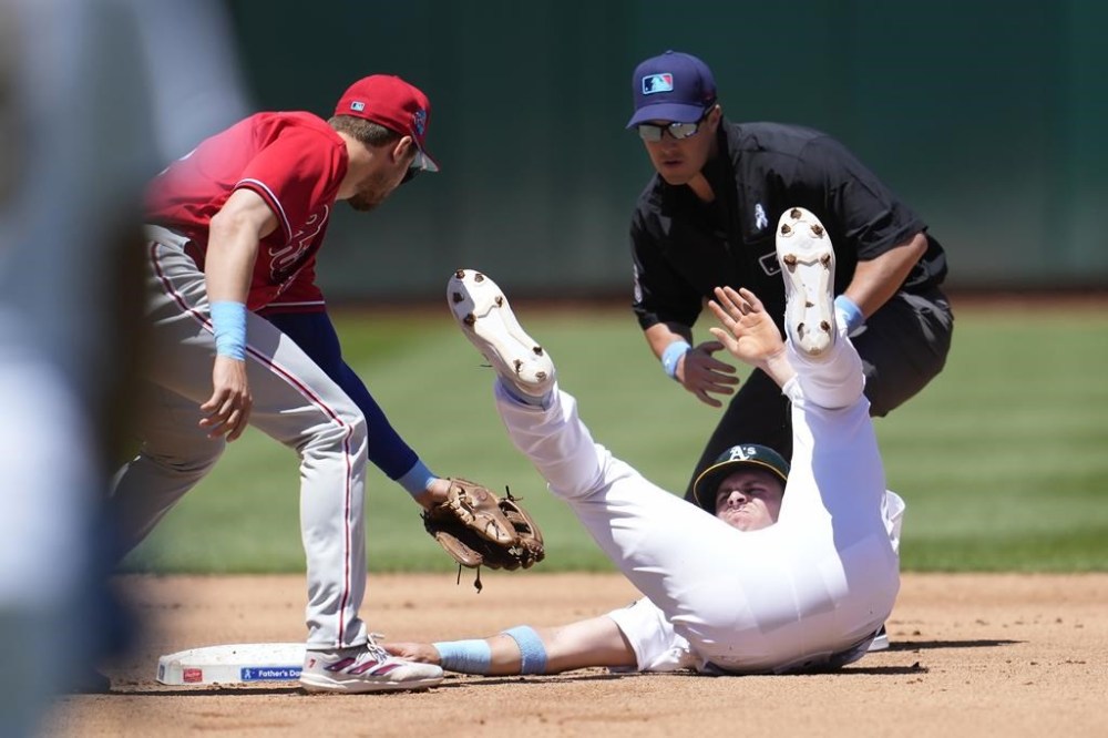 Oakland Athletics' JJ Bleday, bottom right, steals second base next to Philadelphia Phillies shortstop Trea Turner, left, and umpire Brennan Miller during the fourth inning of a baseball game in Oakland, Calif., Sunday, June 18, 2023. (AP Photo/Jeff Chiu)