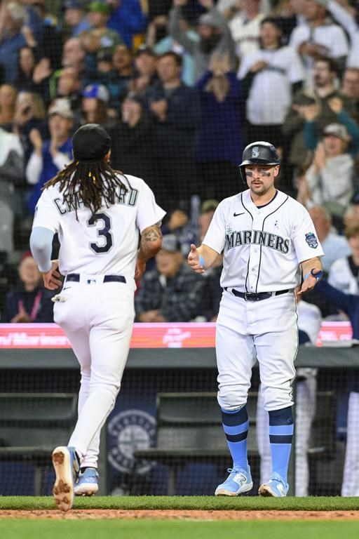 Seattle Mariners' Cal Raleigh awaits J.P. Crawford (3) at home as the pair score off a double by Julio Rodriguez during the third inning of a baseball game against the Chicago White Sox, Sunday, June 18, 2023, in Seattle. (AP Photo/Caean Couto)