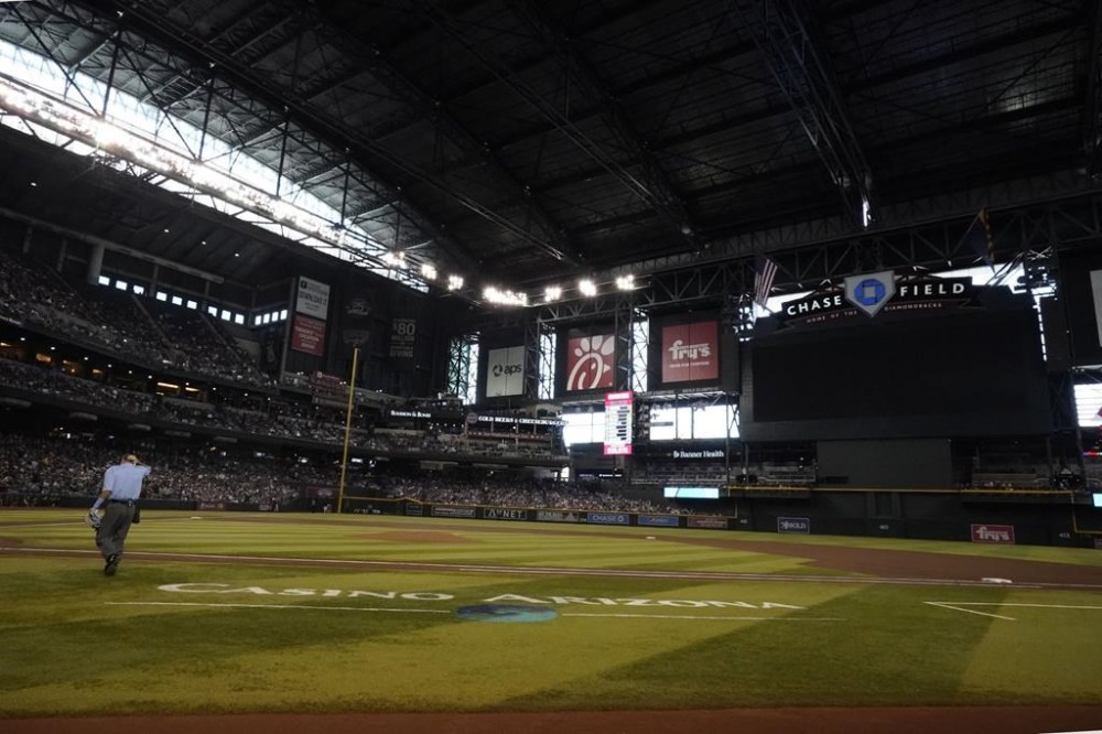 Home plate umpire Pat Hoberg has the field to himself as a lighting issue causes an interruption in play in the first inning of a baseball game between the Arizona Diamondbacks and the Cleveland Guardians, Sunday, June 18, 2023, in Phoenix. (AP Photo/Darryl Webb)
