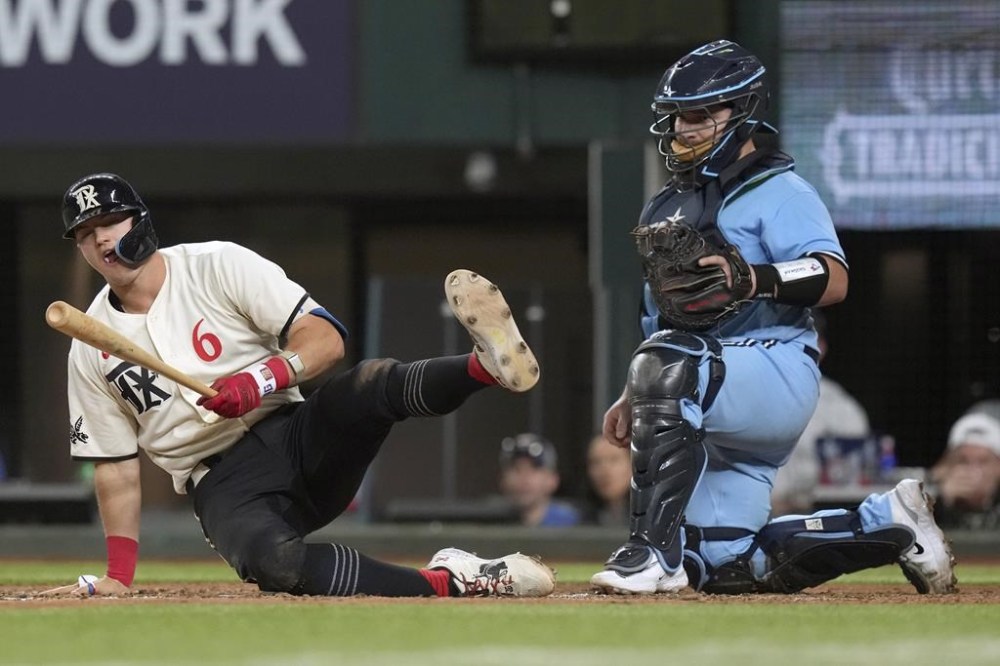Texas Rangers' Josh Jung (6) falls in front of Toronto Blue Jays catcher Alejandro Kirk after taking a strike during the sixth inning of a baseball game in Arlington, Texas, Friday, June 16, 2023. (AP Photo/LM Otero)