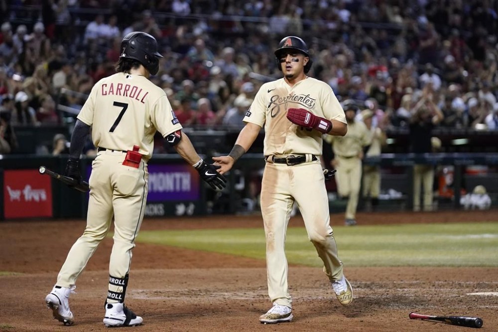 Arizona Diamondbacks' Josh Rojas, right, celebrates with Corbin Carroll (7) after scoring against the Cleveland Guardians during the seventh inning of a baseball game Friday, June 16, 2023, in Phoenix. The Diamondbacks won 5-1. (AP Photo/Ross D. Franklin)