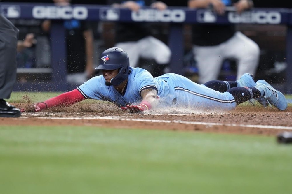 Toronto Blue Jays' Santiago Espinal scores on a single by Ernie Clement against the Miami Marlins during the eighth inning of a baseball game Tuesday, June 20, 2023, in Miami. (AP Photo/Lynne Sladky)