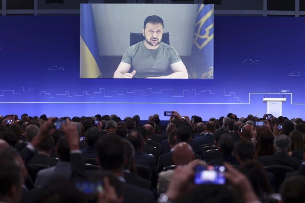 Ukraine President Volodymyr Zelenskyy addresses delegates at the opening session on the first day of the Ukraine Recovery Conference via video, in London, Wednesday, June 21, 2023. Ukraine’s allies pledged several billion dollars in non-military aid on Wednesday to rebuild its war-ravaged infrastructure, fight corruption and help pave the country's road to membership in the European Union. (Henry Nicholls/Pool Photo via AP)