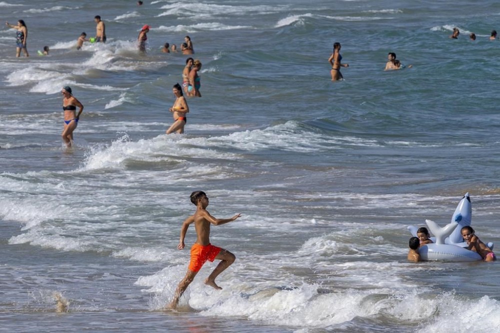 FILE - People cool off on Puerto de Sagunto beach in Spain, Tuesday, Aug. 16, 2022. (AP Photo/Alberto Saiz, File)