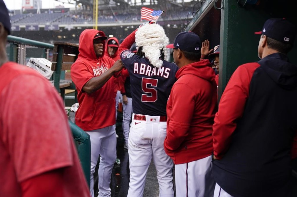 Washington Nationals CJ Abrams puts on a wig and celebrates after scoring on a solo home run in the rain during the fifth inning of a baseball game against the St. Louis Cardinals at Nationals Park, Wednesday, June 21, 2023, in Washington. (AP Photo/Andrew Harnik)