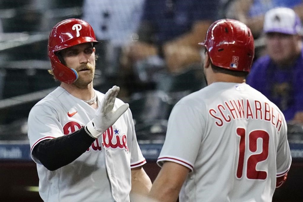 Philadelphia Phillies' Kyle Schwarber (12) gets a high-five from Bryce Harper after Schwarber hit a home run against the Arizona Diamondbacks during the first inning of a baseball game Tuesday, June 13, 2023, in Phoenix. (AP Photo/Ross D. Franklin)