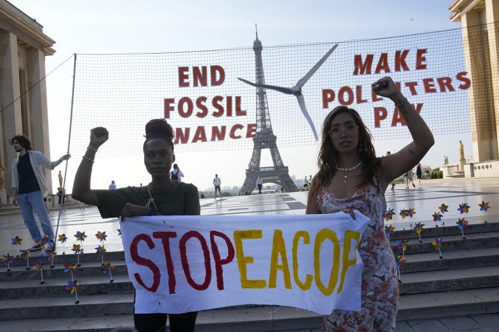 FILE - Climate activists Patience Nabukalu, of Uganda, left, and Mitzi Jonelle Tan, of the Philippines, participate in a demonstration ahead of the Global Climate Finance Summit, Wednesday, June 21, 2023 in Paris. The aim of a two-day climate and finance summit in Paris that ends Friday, June 23, was to set up concrete measures to help poor and developing countries better tackle issues like poverty and climate change. (AP Photo/Michel Euler, File)