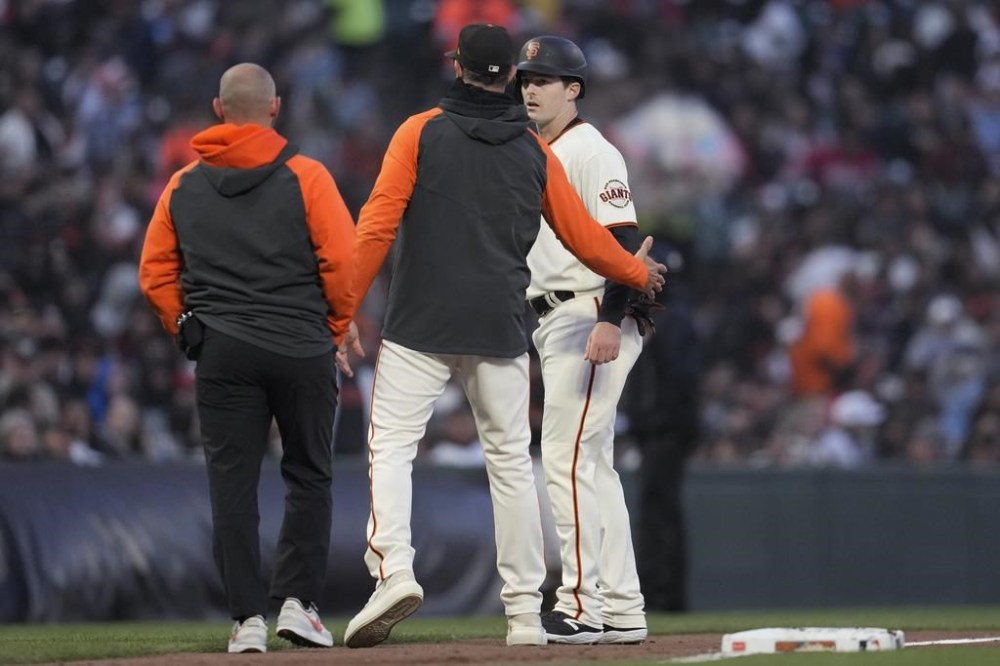 San Francisco Giants' Mike Yastrzemski, right, walks off the field with manager Gabe Kapler, middle, and a trainer during the fifth inning of the team's baseball game against the San Diego Padres in San Francisco, Wednesday, June 21, 2023. (AP Photo/Jeff Chiu)