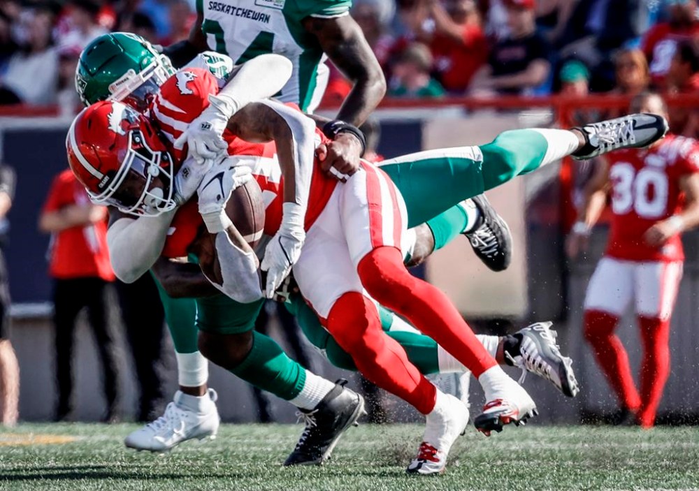 Saskatchewan Roughriders linebacker Larry Dean, centre, brings down Calgary Stampeders receiver Malik Henry during first half CFL football action in Calgary, Alta., Saturday, June 24, 2023. Henry announced Sunday on Twitter that he ruptured his Achilles in Saturday's loss to the Saskatchewan Roughriders. THE CANADIAN PRESS/Jeff McIntosh