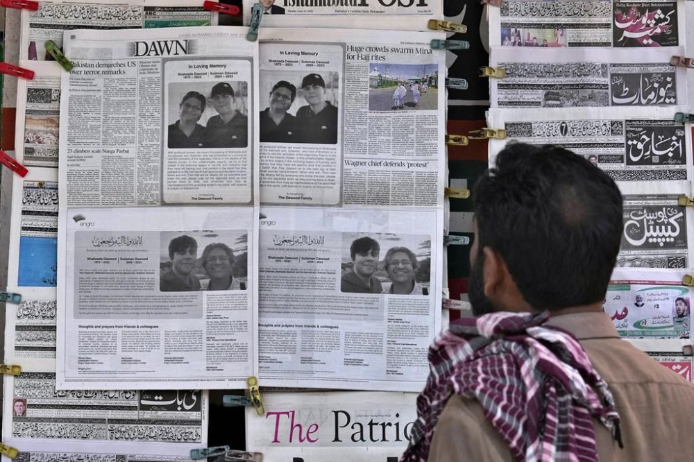 A man looks at morning newspapers as some papers published an ad of condolence massages for two victims of Titan submersible incident, Shahzada Dawood and his son Suleman Dawood, by their family and firm, at a roadside stall, in Islamabad, Pakistan, Tuesday, June 27, 2023. As an international group of agencies investigates why the Titan submersible imploded while carrying five people to the Titanic wreckage, U.S. maritime officials say they'll issue a report aimed at improving the safety of submersibles worldwide. (AP Photo/Anjum Naveed)