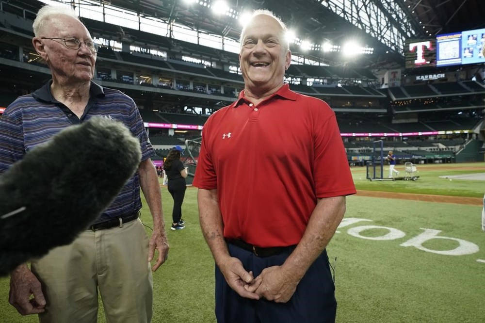 Former Major League pitcher David Clyde, right, laughs while speaking to reporters with fellow former pitcher Bill Gogolewski before a baseball game between the Detroit Tigers and Texas Rangers in Arlington, Texas, Tuesday, June 27, 2023. This is 50th anniversary of Clyde's MLB debut as an 18-year-old kid, the No. 1 overall draft pick. He won that game with eight strikeouts in five innings before Goglewski pitched four innings for a save. (AP Photo/LM Otero)