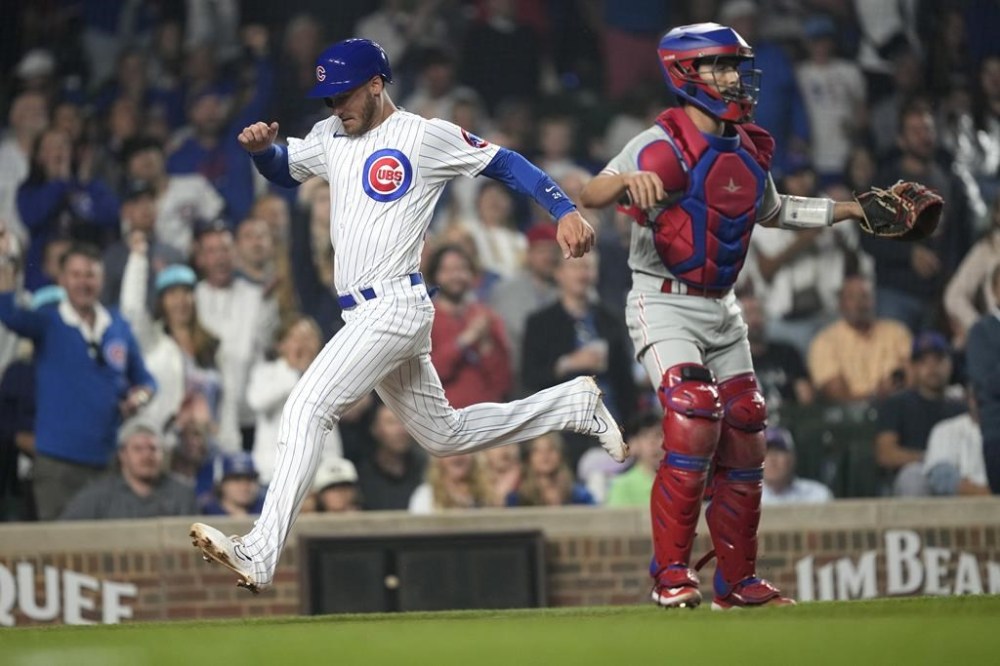 Chicago Cubs' Cody Bellinger scores behind Philadelphia Phillies catcher Garrett Stubbs during the eighth inning of a baseball game Tuesday, June 27, 2023, in Chicago. (AP Photo/Charles Rex Arbogast)
