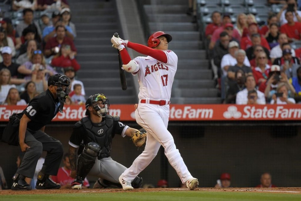 Los Angeles Angels' Shohei Ohtani, right, hits a solo home run as Chicago White Sox catcher Yasmani Grandal, center, and home plate umpire Roberto Ortiz watch during the first inning of a baseball game Tuesday, June 27, 2023, in Anaheim, Calif. (AP Photo/Mark J. Terrill)
