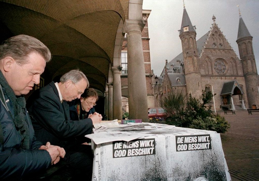 FILE - Protesters pray outside Dutch government buildings in The Hague, Netherlands, on Monday, April 9, 2001, as the Upper House of Parliament began debating registration that will legalize euthanasia under strict guidelines. Slogan on table reads,