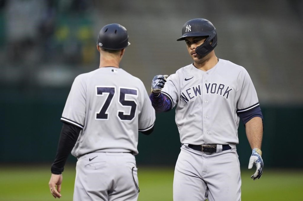 New York Yankees' Giancarlo Stanton, right, celebrates with first base coach Travis Chapman after hitting a two-run single against the Oakland Athletics during the fifth inning of a baseball game in Oakland, Calif., Wednesday, June 28, 2023. (AP Photo/Godofredo A. Vásquez)