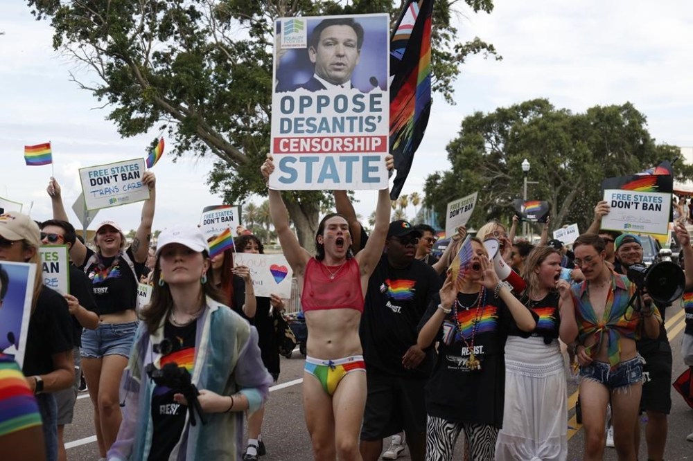 Parade participants carrying signs opposing Gov. Ron DeSantis during the St. Pete Pride Parade along Bayshore Drive on Saturday, June 24, 2023, in St. Petersburg, Fla. (Jefferee Woo/Tampa Bay Times via AP)