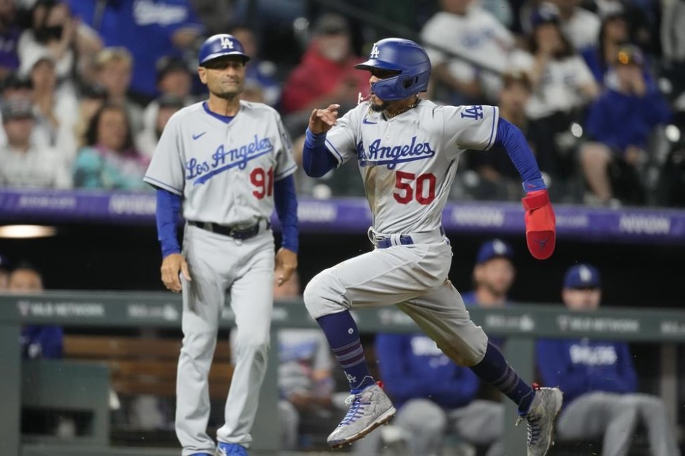 Los Angeles Dodgers' Mookie Betts dashes past third base coach Dino Ebel to score on a single by Freddie Freeman against the Colorado Rockies during the fifth inning of a baseball game Thursday, June 29, 2023, in Denver. (AP Photo/David Zalubowski)