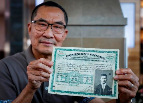 Matthew Yan holds his father's identification certificate from 1920, showing he had paid a $500 head tax, in Calgary, Friday, June 30, 2023.THE CANADIAN PRESS/Jeff McIntosh