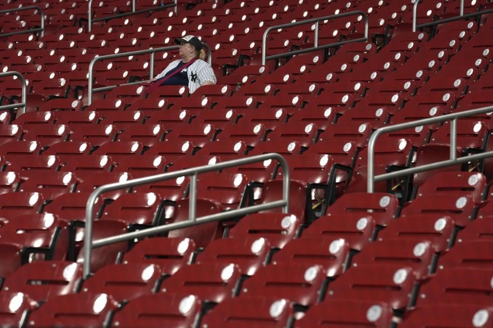 A person wearing a New York Yankees jersey sits in the stands as rain begins to fall, threatening the scheduled start of a baseball game between the St. Louis Cardinals and the New York Yankees Friday, June 30, 2023, in St. Louis. (AP Photo/Jeff Roberson)