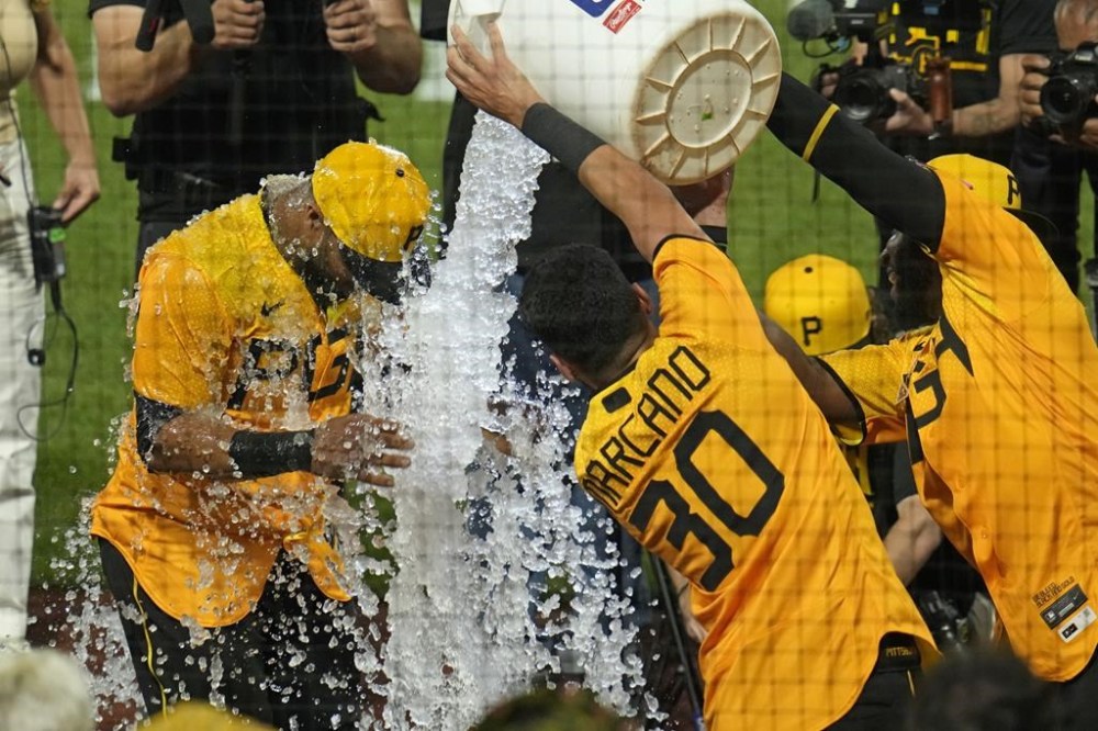 Pittsburgh Pirates' Carlos Santana, left, is doused with ice water after hitting a two-run walkoff home run off Milwaukee Brewers relief pitcher Matt Bush during the bottom of the ninth inning of a baseball game in Pittsburgh, Friday, June 30, 2023. (AP Photo/Gene J. Puskar)