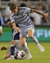 Sporting Kansas City forward Marinos Tzionis, front, and Vancouver Whitecaps midfielder Ryan Gauld (25) battle for the ball during the second half of an MLS soccer match Saturday, July 1, 2023, in Kansas City, Kan. Sporting KC won 3-0. (AP Photo/Charlie Riedel)