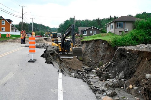 Crews begin repairs to a washed-out section of Highway 170 in Rivière-Éternité, Que., Sunday, July 2, 2023. The search for two people swept away by a landslide in Quebec's Saguenay-Lac-St-Jean region is stretching into a third day. THE CANADIAN PRESS/Jacques Boissinot