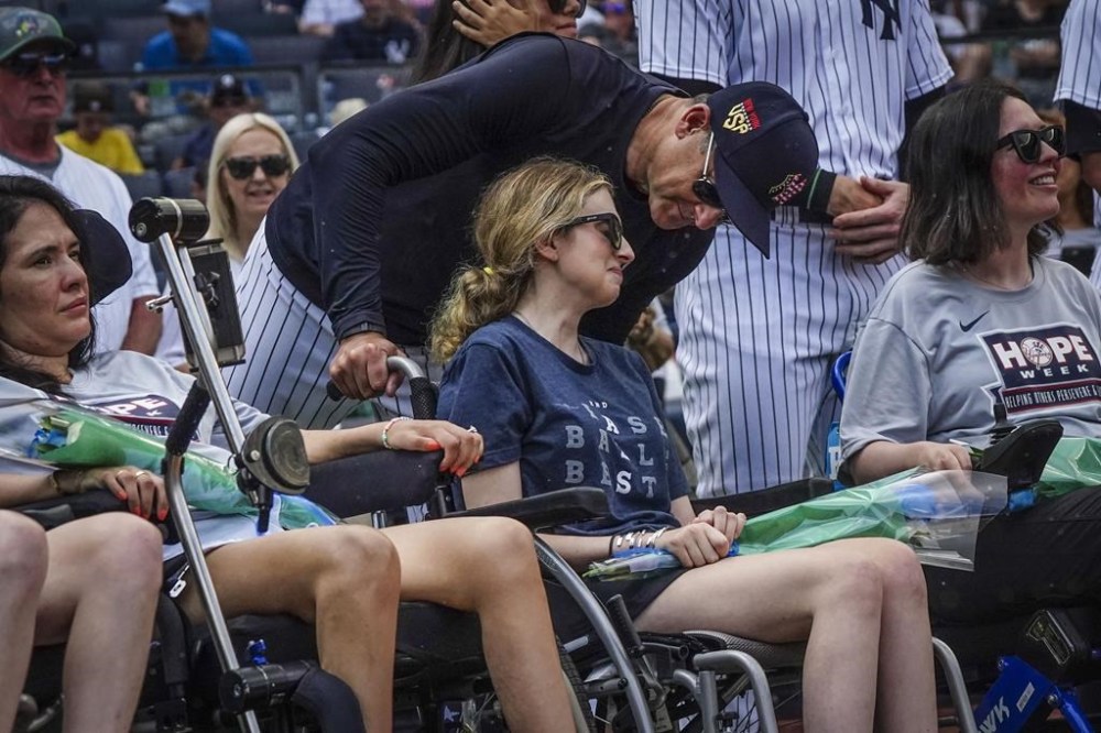 New York Yankees manager Aaron Boone, center, talk with Sarah Langs, their HOPE Week honoree, on the 84th anniversary of Lou Gehrig making his famous