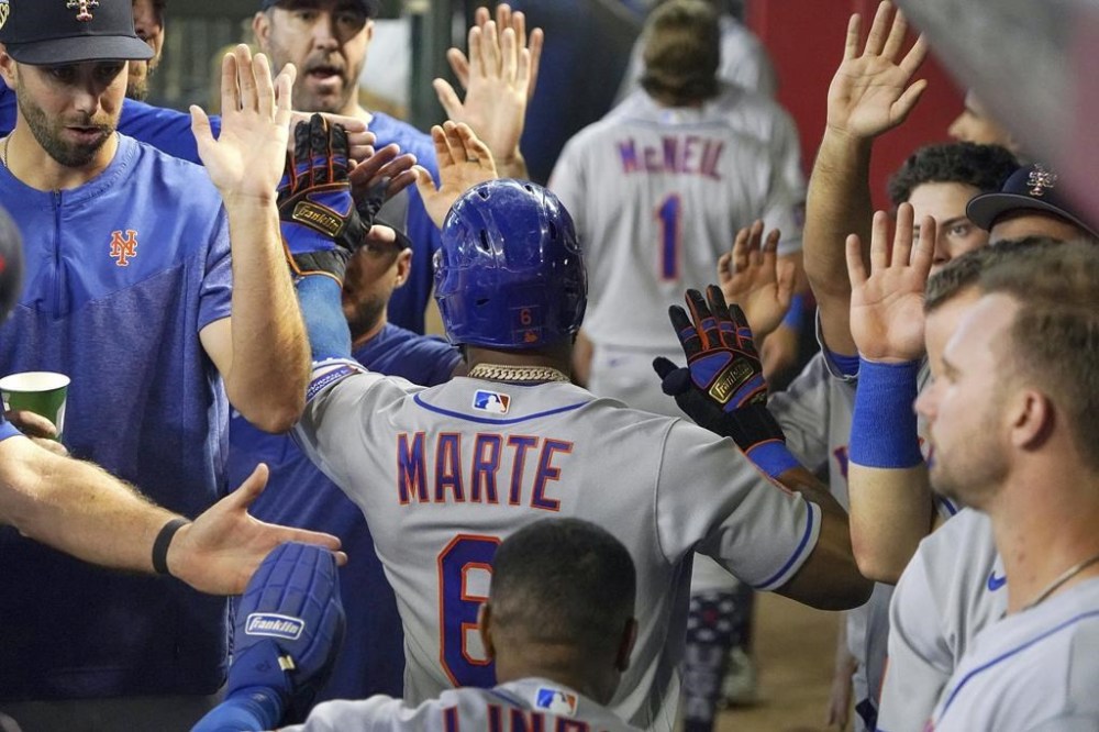 New York Mets' Starling Marte is greeted by teammates after hitting a three-run home run against the Arizona Diamondbacks during the fourth inning of a baseball game Tuesday, July 4, 2023, in Phoenix. (AP Photo/Darryl Webb)