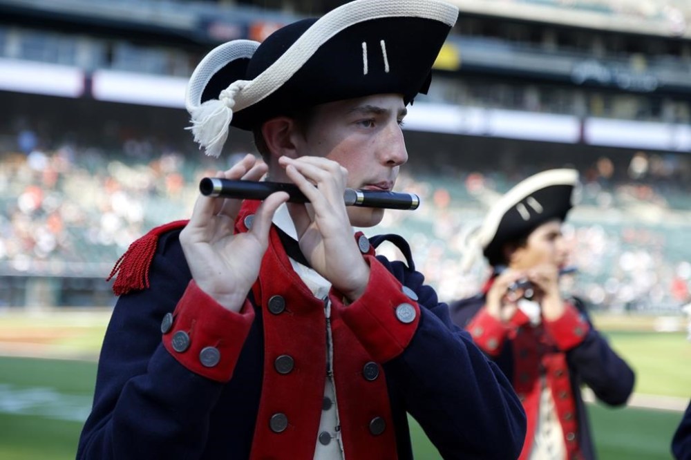 A member of the the Plymouth Fife and Drum Corps, from Plymouth, Mich., plays his fife while entertaining fans for Independence Day, before the Detroit Tigers' baseball game against the Oakland Athletics on Tuesday, July 4, 2023, in Detroit. (AP Photo/Duane Burleson)