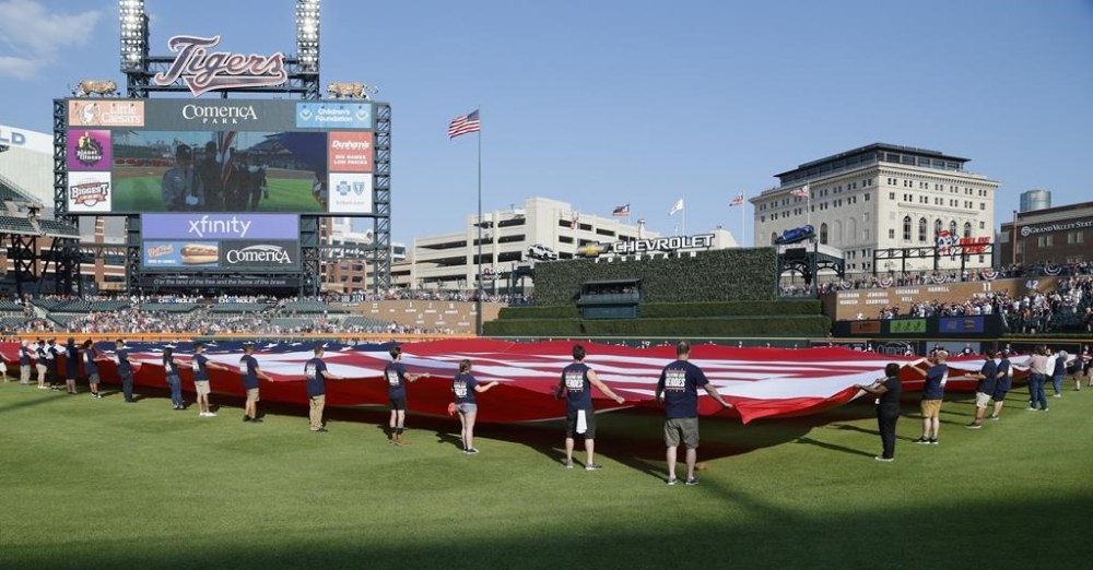 A U.S. flag is unfurled during the national anthem for the Detroit Tigers' baseball game against the Oakland Athletics on Independence Day, Tuesday, July 4, 2023, in Detroit. (AP Photo/Duane Burleson)