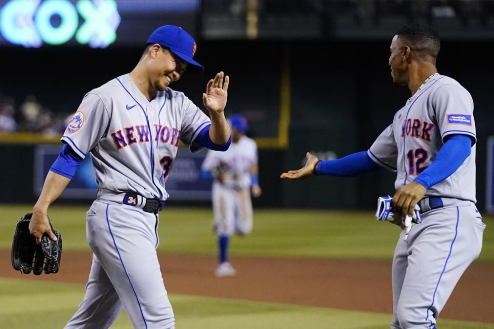 After Arizona Diamondbacks' Alek Thomas flew out, New York Mets starting pitcher Kodai Senga smiles as he slaps hands with shortstop Francisco Lindor (12) during the fifth inning of a baseball game Wednesday, July 5, 2023, in Phoenix. (AP Photo/Ross D. Franklin)
