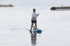 A dog peeks between the legs of a paddle boarder on the Toronto waterfront, Thursday July 6, 2023. A cold front passing through Ontario and Quebec is expected offer relief today after a multi-day heat wave. THE CANADIAN PRESS/Cole Burston