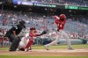Cincinnati Reds' Elly De La Cruz singles in front of Washington Nationals catcher Riley Adams and umpire Manny Gonzalez in the second inning of a baseball game, Thursday, July 6, 2023, in Washington. (AP Photo/Patrick Semansky)