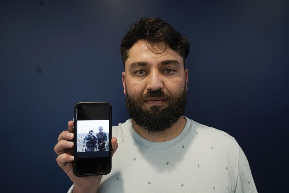 Mohammad Ahmadi poses for a portrait in Alexandria, Va., Friday, July 7, 2023, while holding a phone showing a digital photograph of his relative Nasrat Ahmad Yar who was shot and killed on July 3, in Washington, while working as a ride-share driver. Ahmad Yar was an Afghan immigrant who'd worked as an interpreter for the U.S. military in Afghanistan. (AP Photo/Serkan Gurbuz)
