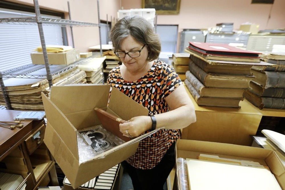 New Bedford Public Library Director Olivia Melo, pulls the 100 year overdue book from the box shipped to New Bedford, Mass., from West Virginia University Library on Friday, July 7, 2023.