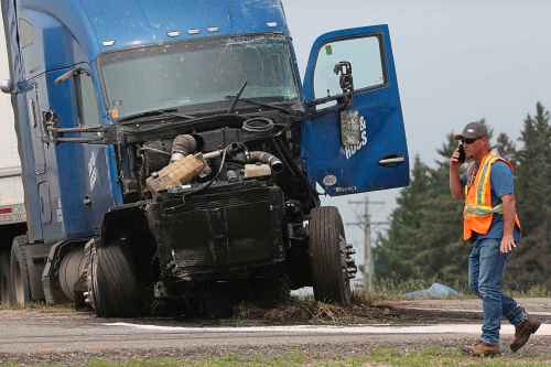 An emergency worker walks passed a semi truck that was involved in a deadly collision Thursday with a small bus carrying seniors at the corner of Highway 5 and the Trans-Canada Highway. The semi had the right of way, police say. (Matt Goerzen/The Brandon Sun)