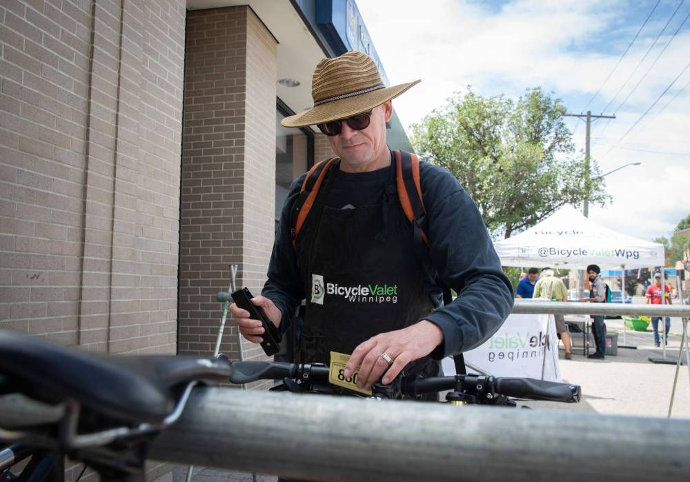 JESSICA LEE / WINNIPEG FREE PRESS
Steve West of Bicycle Valet Winnipeg secures a bike Saturday while its owner explores the businesses along Sargent Avenue.