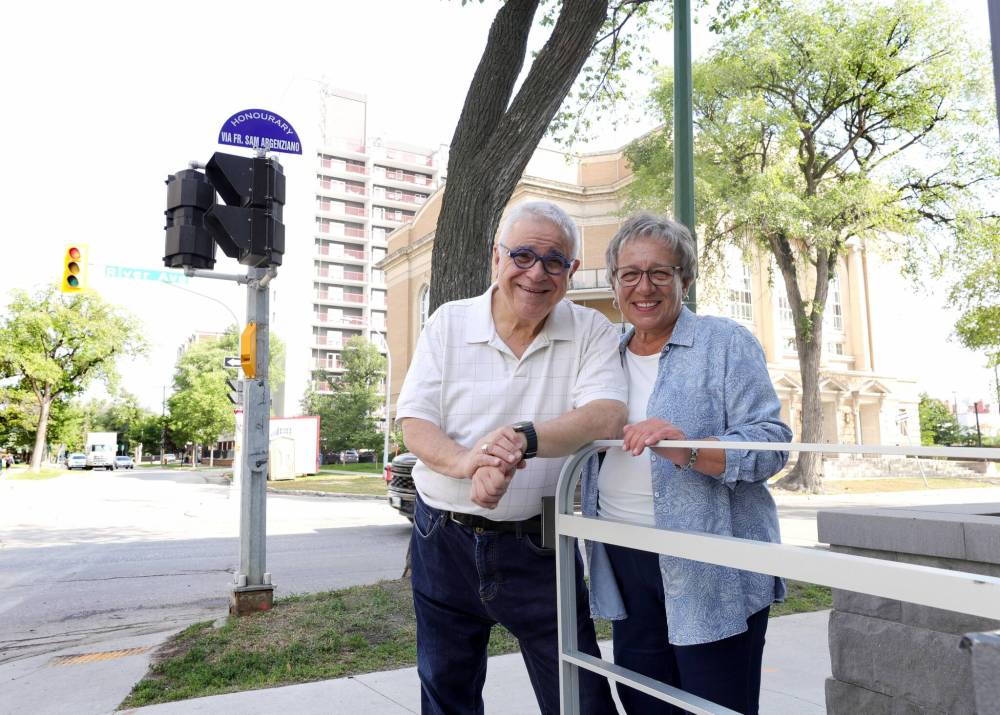 RUTH BONNEVILLE / WINNIPEG FREE PRESS
Rev. Sam Argenziano and parishioner Maria Doerr, who chose the wording when applying for the honorary naming, stand next to the street sign at River Avenue and Nassau Street North that honours the well-known Winnipeg Catholic priest.