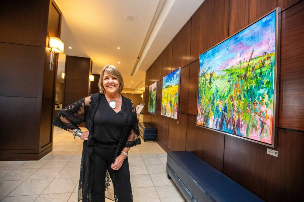 MIKAELA MACKENZIE / WINNIPEG FREE PRESS
Fairmont artist-in-residence Amanda Onchulenko with her paintings in the hotel lobby in Winnipeg on Tuesday, July 25.