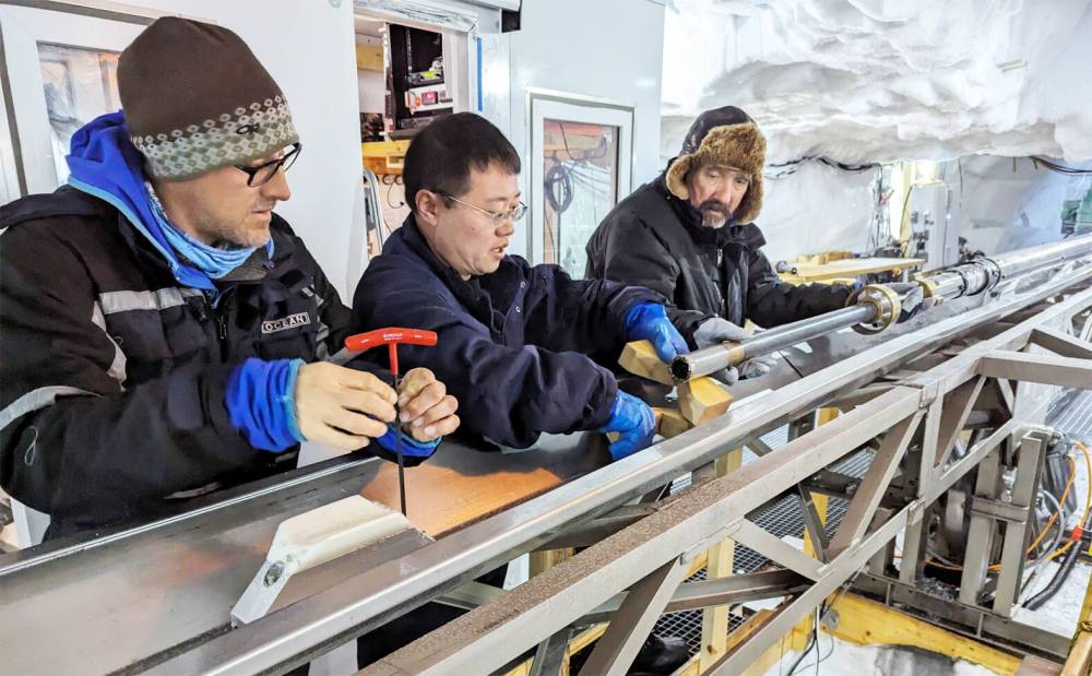 DORTHE DAHL-JENSEN PHOTO
The rock drill being mounted on the drill tower. On the picture Trevor Popp, Nan Zheng (Jilin University, China), Steffen Bo Hansen (University of Copenhagen).